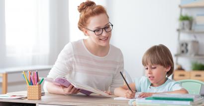 Primary teacher supporting primary pupil with their work to assess them